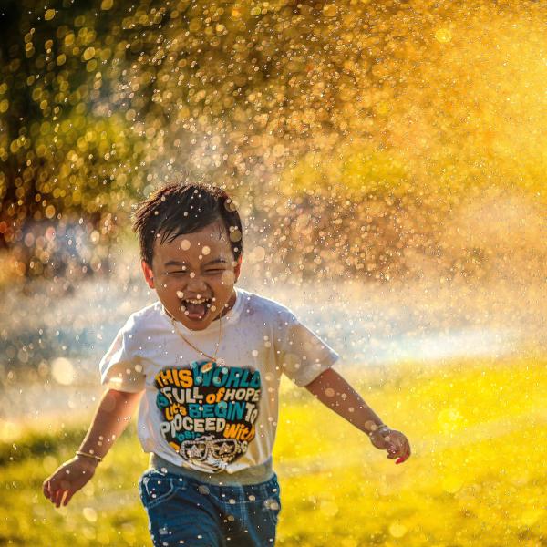 Child playing in sprinkler