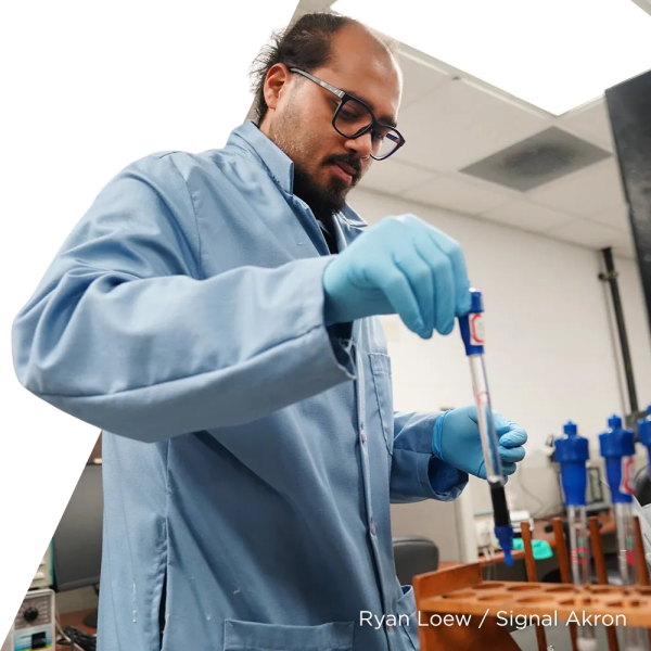 Moni Mahesh Ghosh, a Ph.D. candidate at the Akron University of Akron School of Polymer Science and Polymer Engineering, handles containers used for rapid testing of PFAS contaminants in water in a lab at the University of Akron’s Olson Research Center. (Ryan Loew / Signal Akron)