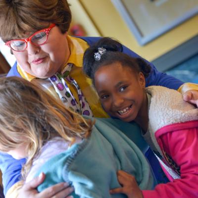 woman hugging two kids
